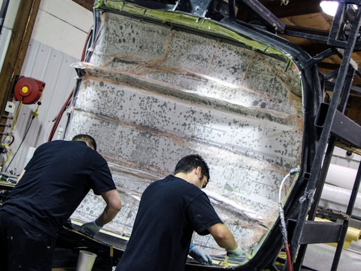 Fabricating a right side fender. Notice the small dots of resin on the hood area. This is resin being squeezed into an absorbent layer under vacuum.