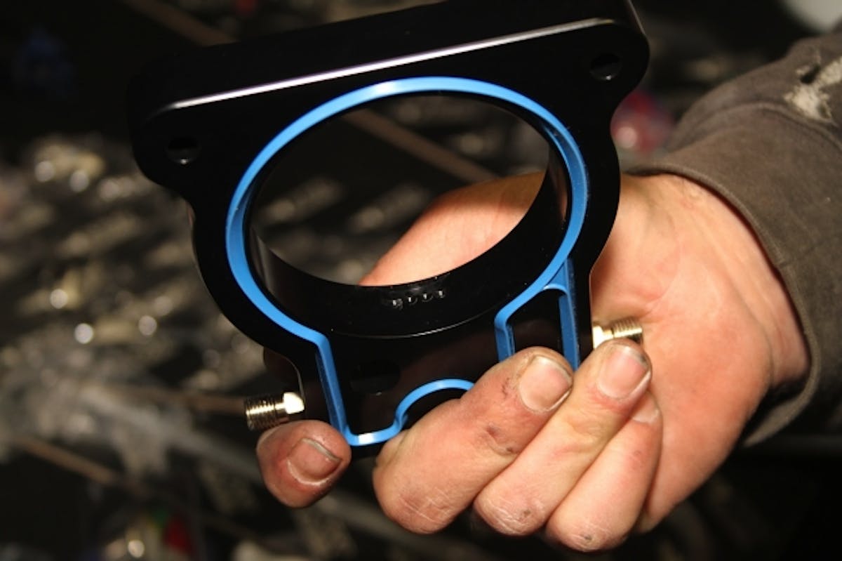 The heart of the system is this billet aluminum plate that has internal machined passages for fuel and nitrous, which mix and are atomized as they exit the four orifices seen here.