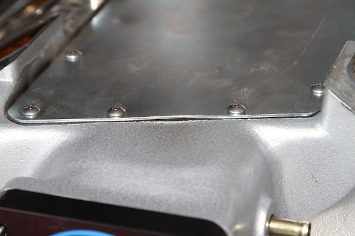 The backfire bulged the seam between the underside plate and the cast manifold body.