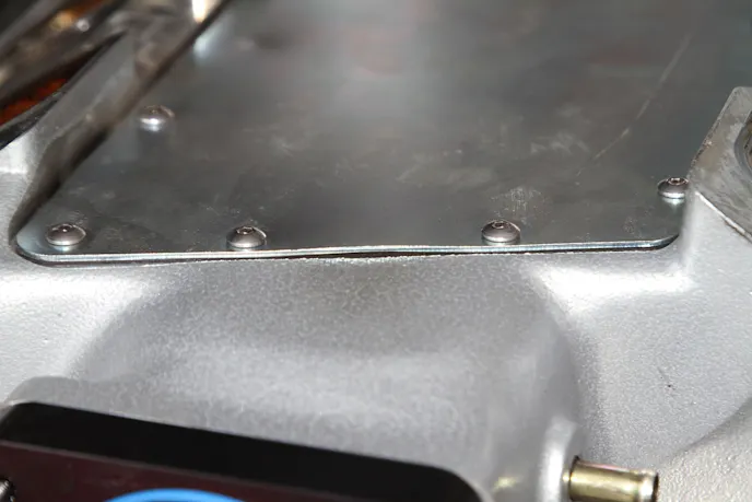 The backfire bulged the seam between the underside plate and the cast manifold body.