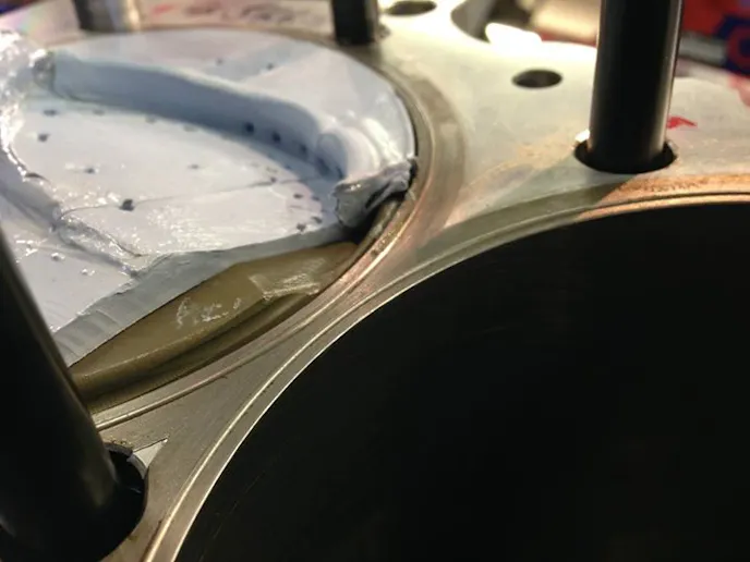 Checking piston-to-valve clearance is done through the use of blu-tac, which covers the piston entirely. The engine is rotated over by hand and the valves leaves an imprint int he material, which is cut away to check thickness and clearance.