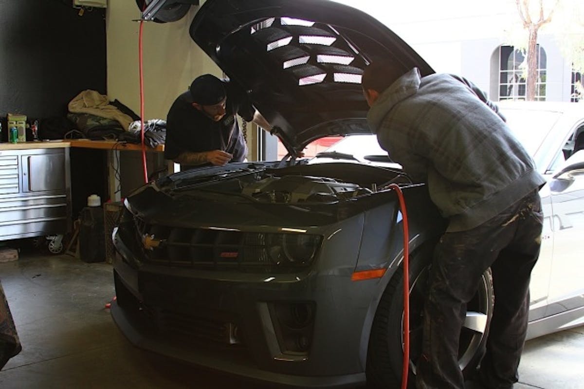 The new hood is situated and installed onto the Camaro. Special care was taken to ensure the latch assembly was not off-center before closing it shut.