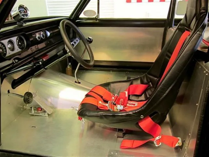 The interior of the Chevy 2 Much re-creation is ready to race with just a single racing bucket, harnesses, and roll cage.