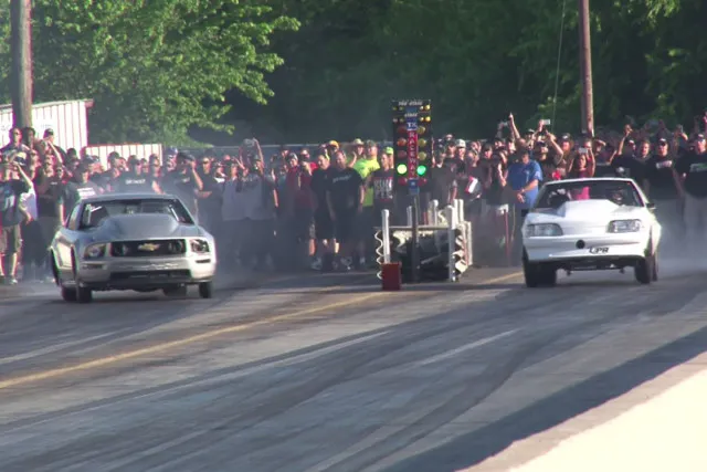 The Two Sides Of No Prep Racing: Aaron Stapleton having issues with his Ford Mustang in the right hand lane (left side of the photo) - again displaying the difficulty of No Prep racing. While Stapleton is smoking the tires and trying to gather his car up to stay in his lane, his opponent has the front wheels up and going right down broadway, straight as a string. 
