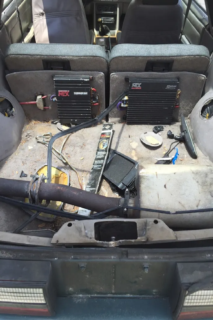 The GT's hatch area shows the makings of an old-school system, a Flowmaster muffler, and miscellaneous other items.