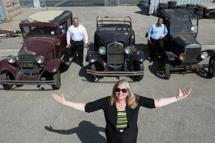 Shown behind Elizabeth Henderson, chief deputy public administrator of Orange County are a 1932 Radio Flyer Model A Ford, a 1020-era Ford Roadster, and a Model T dating from before 1919. These are three of the cars that are the best condition of those that were found. Image courtesy Orange County Register