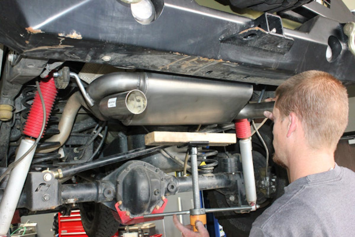 A tall jack stand (with a 2×4 used as a buffer) helped hold the Gibson cat-back system in place while it was being installed.