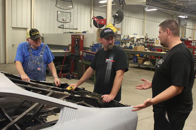 Shane (center) and his father (left) discuss the chassis upgrades with a member of the RJRC Crew.