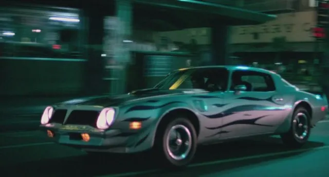A crew of bad guys in a 1974 Trans-Am with some pretty awful side striping.