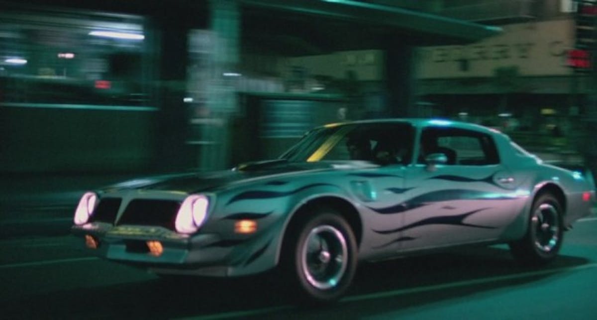A crew of bad guys in a 1974 Trans-Am with some pretty awful side striping.