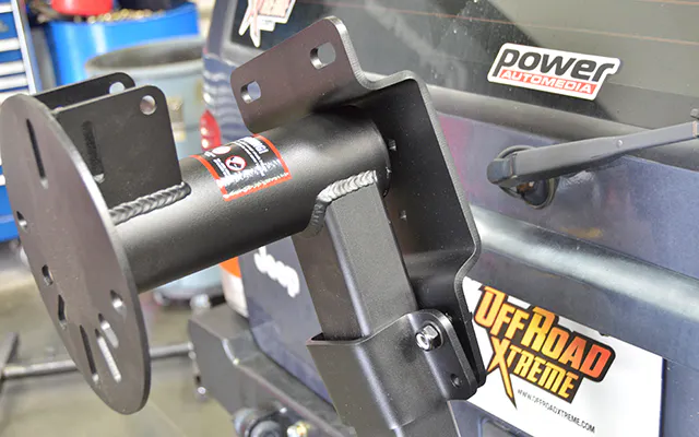 The Rotopax/Hi-Lift bracket clamps to the vertical tube of the swing arm. Position the bracket so the top portion rests on the top tube.