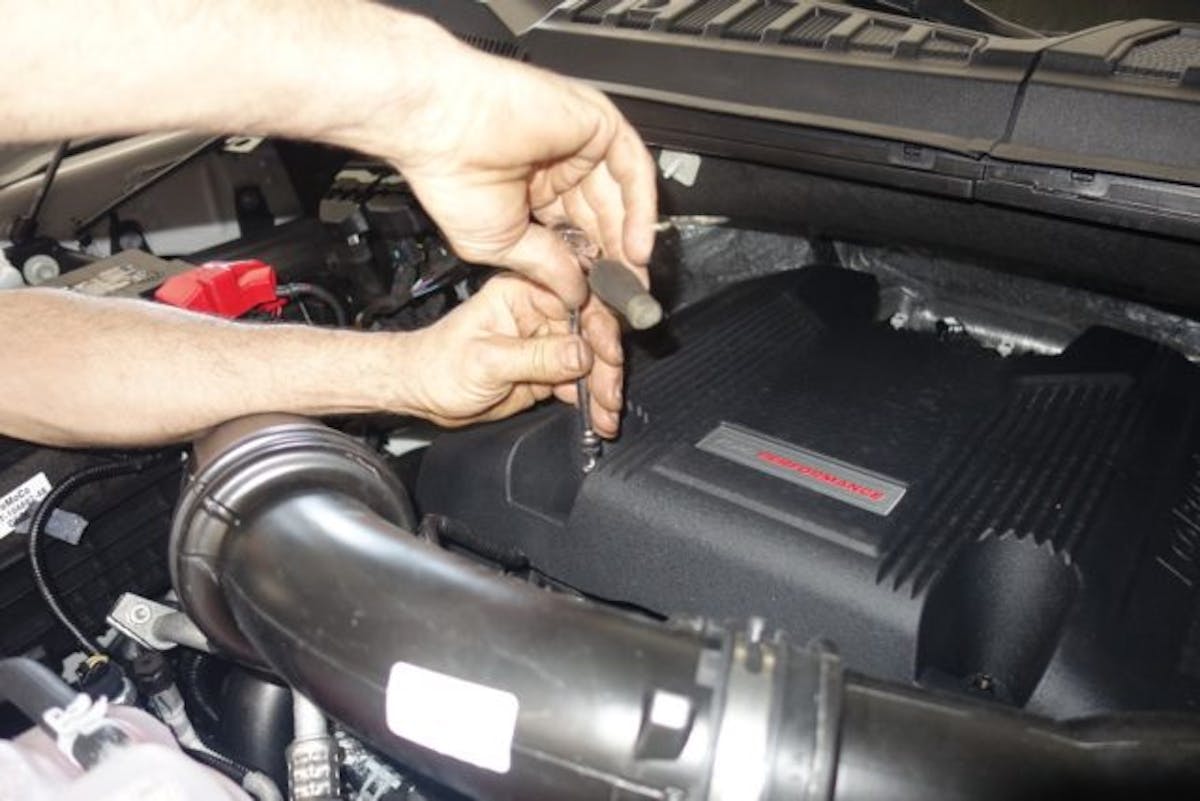 Sarasota Ford’s Senior Master Technician Rick Wiedneroth gets started by disconnecting the battery’s negative battery terminal and removing the Raptor’s factory engine cover.