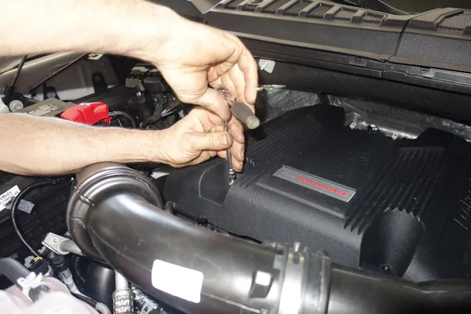 Sarasota Ford’s Senior Master Technician Rick Wiedneroth gets started by disconnecting the battery’s negative battery terminal and removing the Raptor’s factory engine cover.