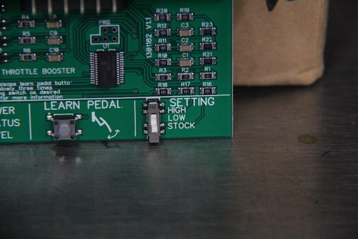 image shows AMP'd Throttle Booster circuit board with sensitivity adjuster and pedal learn button