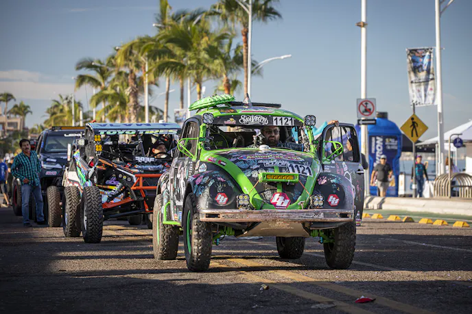 Class 11 racer Dennis Hollenbeck and his #1121 1969 BFGoodrich–equipped Volkswagen Beetle, named "Bochito," await technical inspection. Hollenbeck races to money for the Casa Esperanza, a nonprofit organization helping abused mothers and children.
