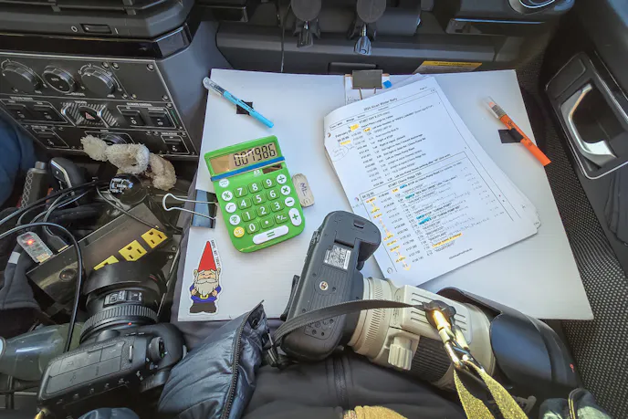 White navigation board for 2024 Alcan 5000 Rally is holding a route book, calculator, and pencils.