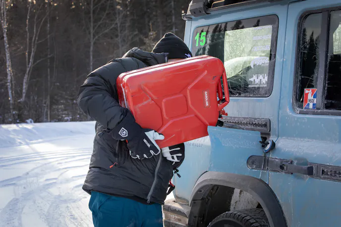 Man filling up SUV with red jerry can during 2024 Alcan 5000 Rally