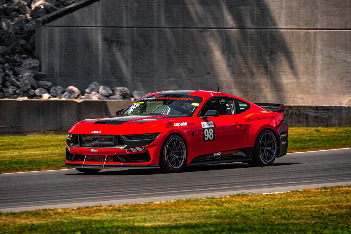Red Ford Mustang racecar on track at speed