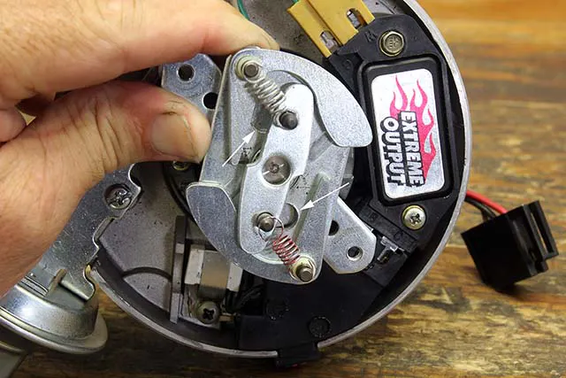 Nearly all distributors use a pin in a slot to determine the amount of mechanical advance allowed. The length of the slot as well as the size of the pin and its bushing limit the amount of advance. This is an HEI distributor, and the arrows indicate the two slots with pins that protrude through the plate. You can lengthen this slot to increase mechanical advance or braze it up to reduce its travel distance to reduce total advance.