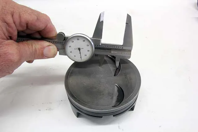 Using the valve centerline marked in the piston, set the valve radius (half of valve diameter) with a set of dividers and scribe a radius around the valve relief. This will indicate if you have sufficient radial clearance. If not, the pocket may need to be machined.