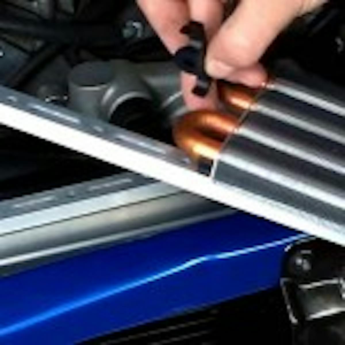 The oil cooler attaches to the center bracket via a set of GatorClips. The GatorClips attach directly to the rigid tubes so that the more fragile fins won't be damaged, which would reduce the cooler's efficiency.