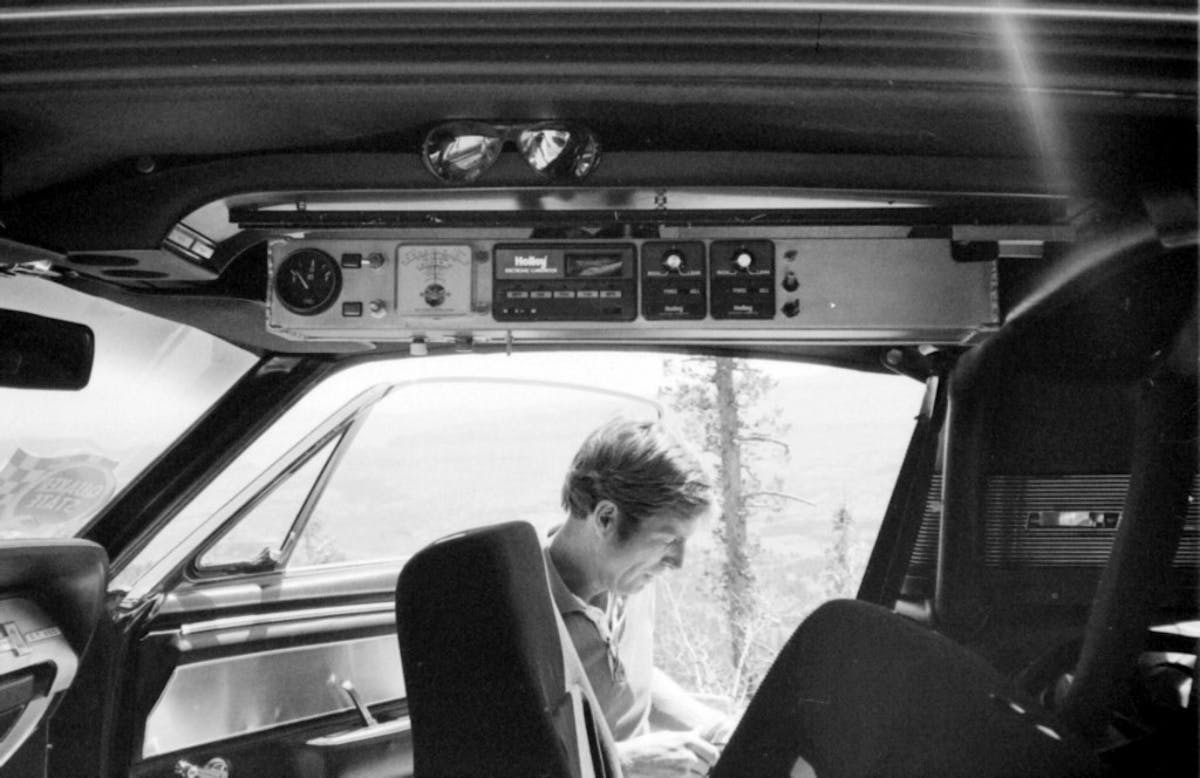 At a brief roadside stop in 1982, RPM plans his next move. Near the car’s headliner is another aluminum panel housing switchgear and gauges for carb tuning and fuel transfer between the tanks. 