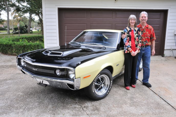 Steve and Pam Gers smile broadly standing next to their other AMX, a yellow and black ’70 model that looks as perfect as the ’69.