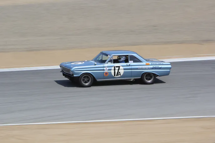 Laguna pan blur This is at speed coming down the hill at Mazda Raceway Laguna Seca after the corkscrew. Note the small black specs at the top of the windshield. These are rubber bumpers that cushion the fiberglass hood because the chrome boat engine cover hinges allow the hood to rotate more than 90 degrees.